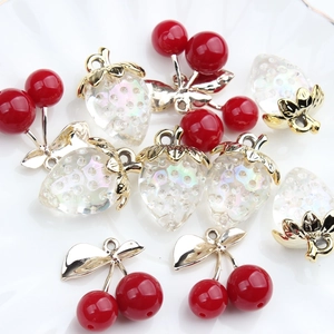 Pearlescent strawberry and red cherry charms for DIY jewelry making on white plate