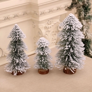 Three snow-dusted tabletop mini Christmas trees on wooden bases for festive decor