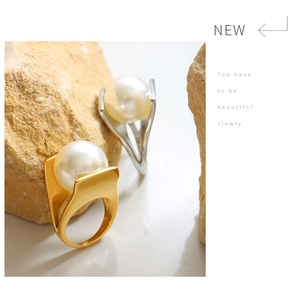 Close-up of gold and silver Y-style wide rings with large pearls on stone decor