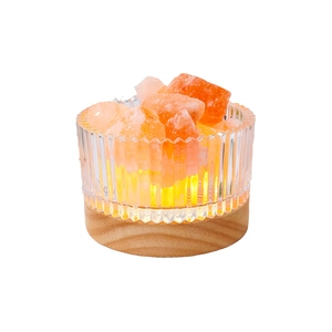 Himalayan salt lamp with orange crystals on wood base and warm glowing ambiance light