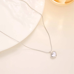 Macro detail of silver heart necklace with white shell inlay and polished chain