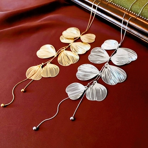 Elegante Gold- und Silberhalsketten mit Ginkgoblättern und Quasten auf rotem Samt