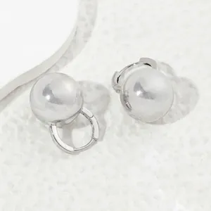 Minimalist silver spherical drop earrings with mirror finish on a geometric stand