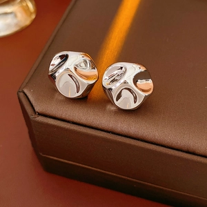 Macro shot of silver round wrinkled earrings with fluid lava texture on leather
