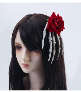 Detail of Gothic red rose hair clip with white skeleton hand on dark hair