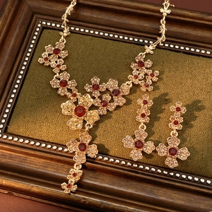 Vintage gold jewelry set with red and champagne crystals on a retro green background