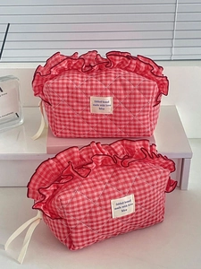 Close-up of red and white checkered quilted makeup bag with decorative red ruffle trim
