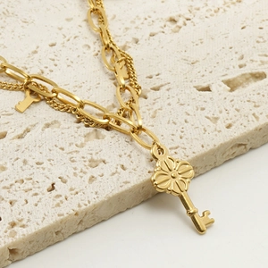 Double-layered 18k gold plated stainless steel key pendant bracelet on beige stone