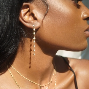 Close-up of elegant gold tassel earrings with zircon stones on model with necklace