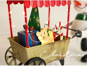 Détail du chariot de Noël lumineux avec mini sapin, cadeaux et lumières LED chaudes