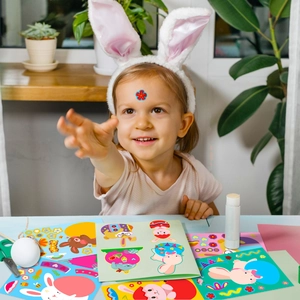 Close-up of a happy girl playing with colorful Easter bunny and egg stickers