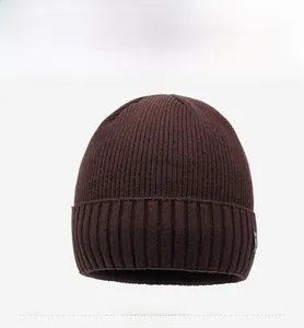 Detail view of dark brown knitted beanie showing vertical rib texture and woven logo tag