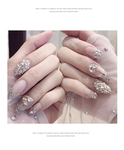 Detail of glittery AB rhinestones and champagne crystals on pink gradient press-on nails