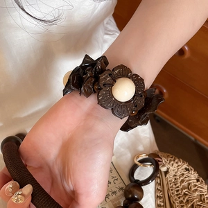 Close-up of vintage coconut shell and wood bead flower bracelet worn on a wrist