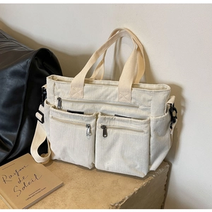 Close-up of beige corduroy tote bag with dual front zipper pockets and shoulder strap