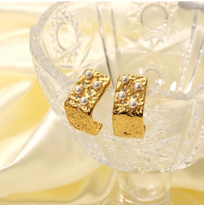 Detail of 18K gold C-shape earrings with pearls and crystals in a glass bowl