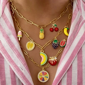 Détail d'un collier doré multicouche avec pendentifs fruits en émail coloré et strass chic