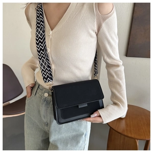 Detail of black rectangular crossbody bag with patterned wide strap and gold hardware