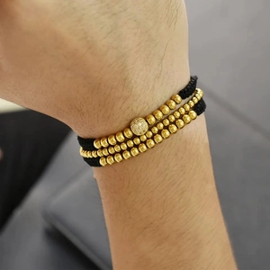 Detail view of gold beaded stacked bracelets with micro-pave zircon on wrist