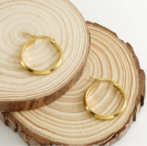 Detailansicht der goldenen Edelstahl-Ohrringe auf natürlichem Holzmaserungshintergrund