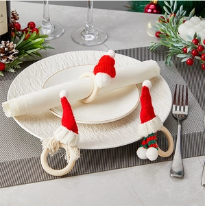 Tre portatovaglioli a forma di cappello di Babbo Natale in maglia su una tavola natalizia