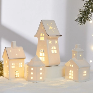 White ceramic light-up Christmas houses on snow base with festive pine needle decor