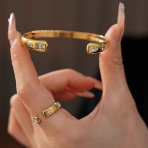 Close-up of gold stainless steel open bangle and ring set with teardrop zircon stones