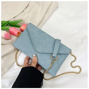 Detail of light blue envelope bag with gold chain strap and textured fabric finish