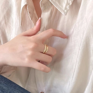 Minimalist double layer gold ring on model finger with elegant fabric background