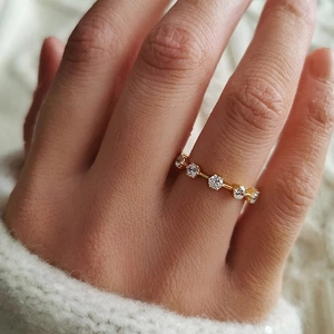 Macro shot of slender gold micro-pave ring with clear zircons worn over a white sweater