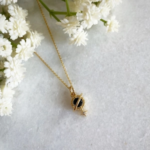 Vintage 18K gold Saturn necklace with black gemstone and star pendant on marble