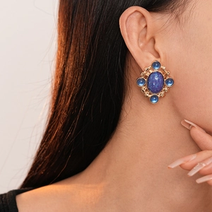Close-up of retro French court style blue oval gemstone earring worn by a model