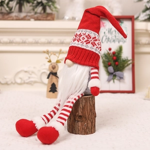 Close-up of plush long-legged Christmas gnome with knitted hat on wooden stool