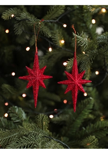 Close-up of red glittery octagonal star ornaments hanging on a festive Christmas tree branch