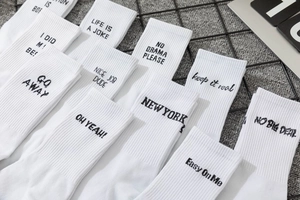 Detail of white cotton crew socks with black letter slogans like Life Is A Joke