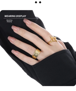 Detail shot of a square peach diamond ring and textured gold band worn on a hand