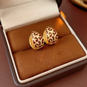 Close-up of gold leopard print hoop earrings displayed in a brown velvet jewelry box