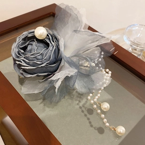 Close-up of blue-grey satin rose hair clip with elegant pearl tassel and vintage detail