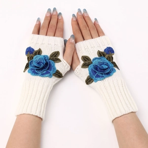 Detail of white knit fingerless gloves featuring blue rose embroidery and knit texture