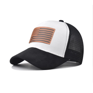 Dettaglio della toppa in pelle con bandiera americana su cappello trucker mesh bianco e nero