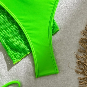 Detail of neon green textured mesh fabric and precision stitching on a bikini swimwear