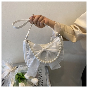 Detail of white fabric handbag featuring large bow and elegant pearl woven handle