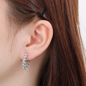 Close-up of elegant C-shaped silver earrings with micro pearls on a model ear