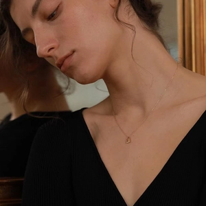 Close-up of a minimalist golden lock pendant necklace worn with a mirror reflection