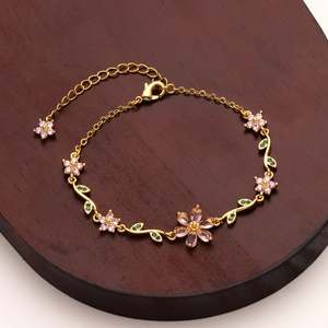 Detailed close-up of a floral chain bracelet with pink cherry blossoms and green crystals