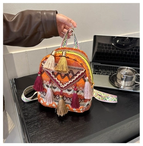 Detail of woven bohemian backpack featuring vibrant multicolored tassels and ethnic patterns