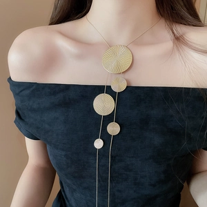 Close-up of long gold fringe necklace with geometric textured round discs for women