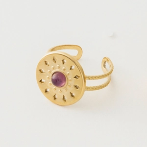 Detail of vintage gold-plated ring featuring purple stone and sunburst engraving