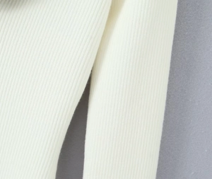Gros plan sur le tissu en maille côtelée blanc crème de cette robe style français