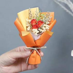 Detail of mini dried rose bouquet with white baby's breath in orange wrapping